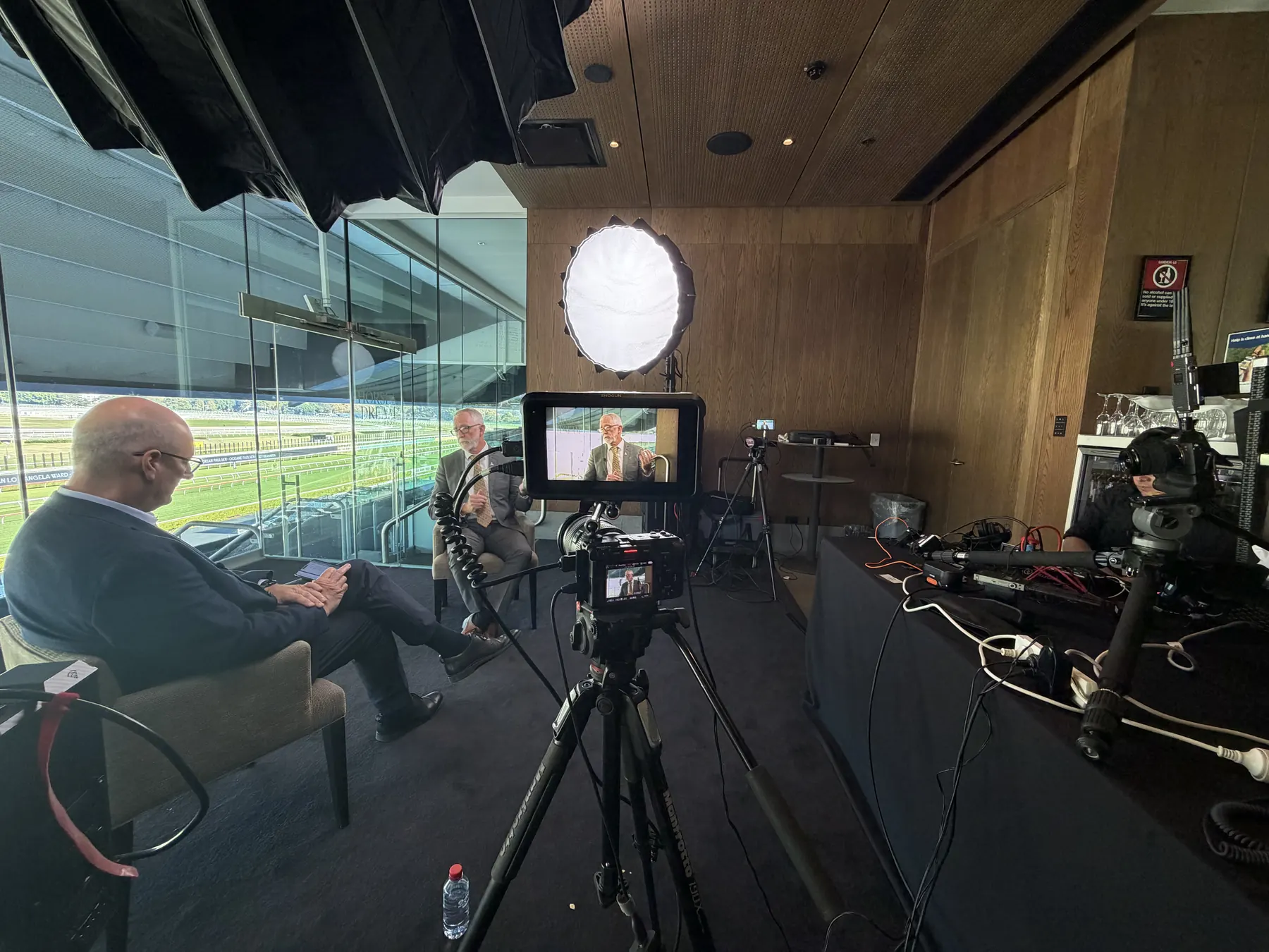 Testimonial video interview setup on location: a customer seated in a lit interview chair with a cinema camera, monitor and softbox, Hey Action Productions